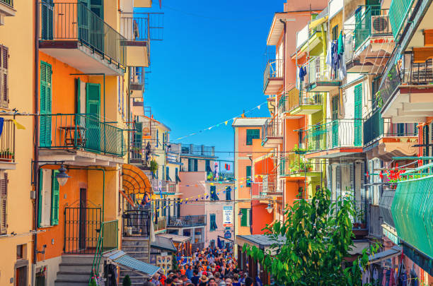 colorful buildings houses with flags rows, balconies, shutter windows on narrow street of typical traditional fishing village national park cinque terre - manarola imagens e fotografias de stock