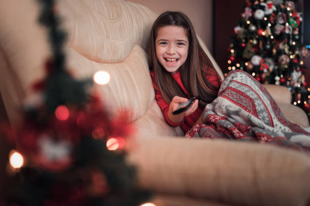istock Excited girl holding remote control when sitting by a Christmas tree 1292107552