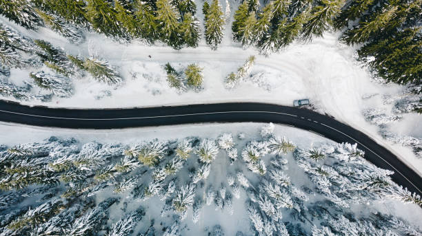 istock Curvy windy road in snow covered forest, top down aerial view 1292109798