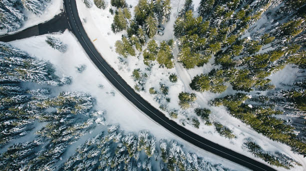 istock Curvy windy road in snow covered forest, top down aerial view 1292109868