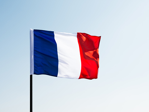 Flag of France waving against blue clear sky.