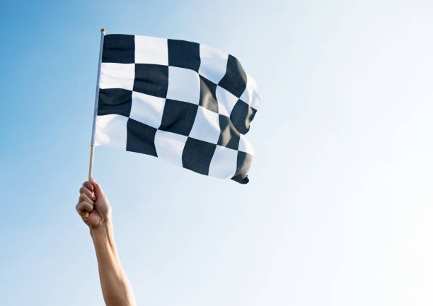 istock Man hand holding checkered flag in the wind 1292111189