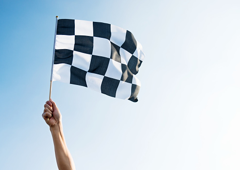 Man hand holding checkered flag in the wind.