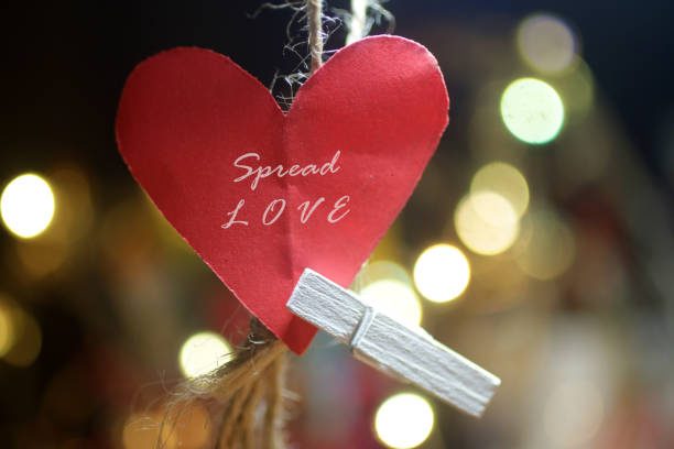 Spread Love. Positive words on red heart paper shape. stock photo