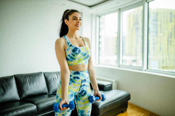 istock Beautiful young woman doing home workout with dumbbells 1292118064