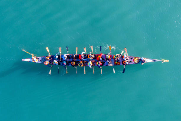 Dragon Boat team rowing to the pace of an onboard Drummer. Haifa, Israel - December 11, 2020: Dragon Boat team rowing to the pace of an onboard Drummer, Aerial view. team stock pictures, royalty-free photos & images