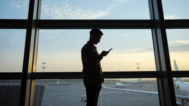 istock Man surfs internet with smartphone near window at airport 1292119496