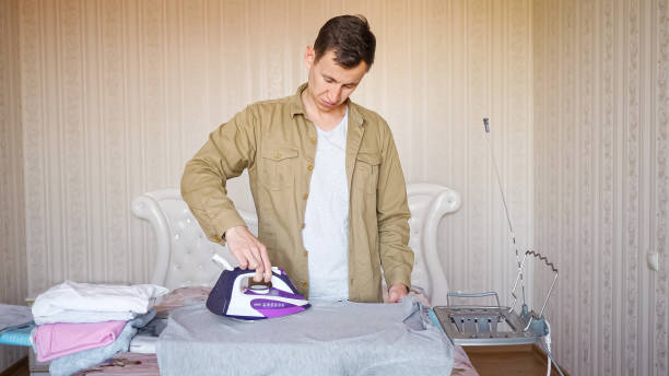 istock young man ironing things on an ironing board for the first time 1292119497