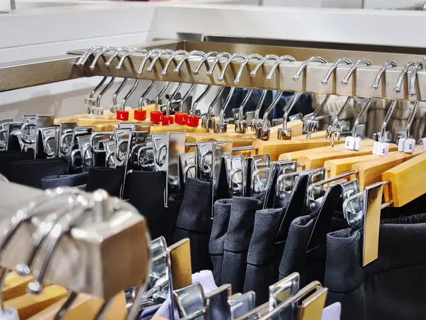 Row of Black Pants with Cloth Hangers at Clothing Store with Selective Focus