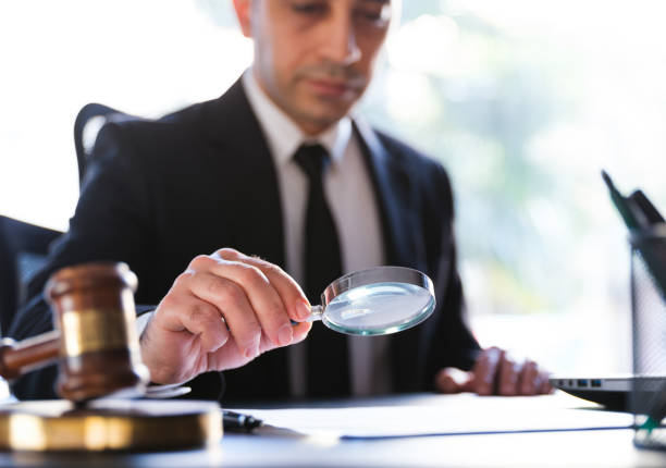 hombre en traje negro leyendo un documento legal cuidadosamente usando la lupa - ajustar fotografías e imágenes de stock