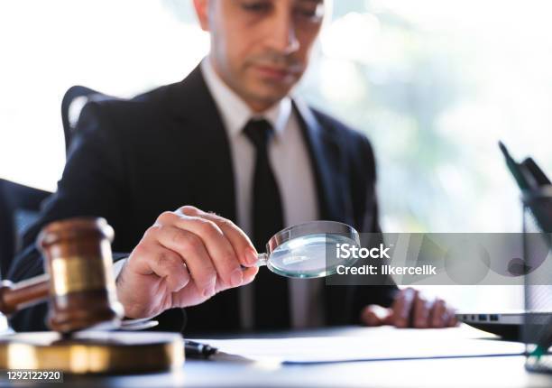 Man In Black Suit Reading A Legal Document Carefully Using Magnifying Glass Stock Photo - Download Image Now