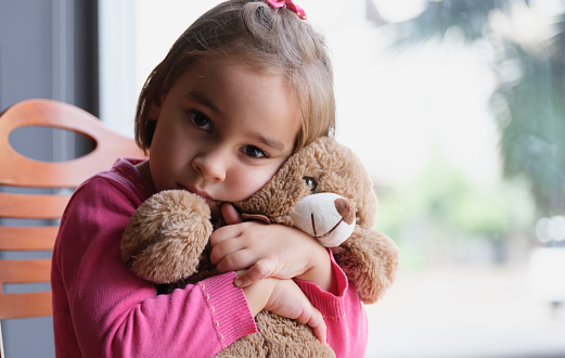 Little Child Girl Hugging Her Toy Bear At Home Nearby Window