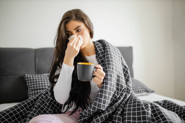 istock Sleeping young sick girl lying on a bed with cold and high fever and drinking tea 1292126849