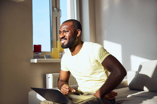 Afro-American male is squinting from the sun Man partly closing his eyes because of the sun while looking outdoors during working on a laptop squint eyes stock pictures, royalty-free photos & images