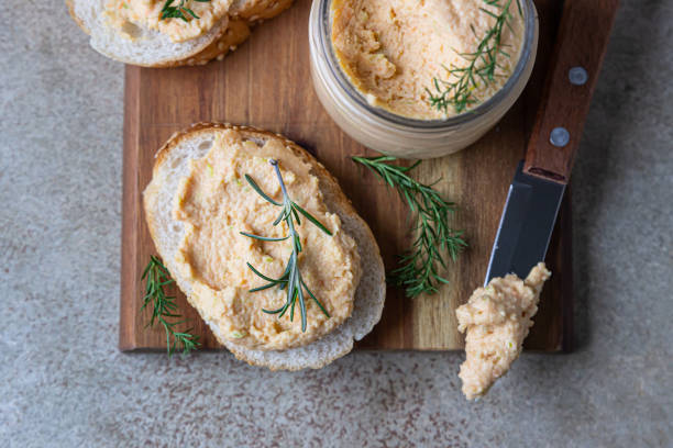 homemade pate, spread or mousse in glass jar with sliced bread and herbs, light concrete background. top view. - crostini imagens e fotografias de stock