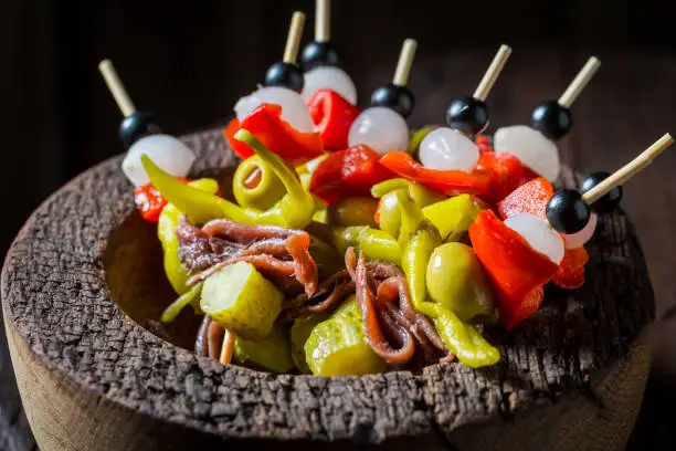 Tasty banderillas made of peppers, anchovies and onion for spanish corrida in wooden bowl