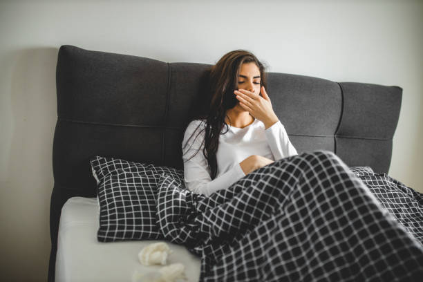 istock Attractive young woman suffering with the flu while sitting on her bed at home 1292134237