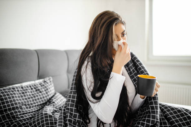 istock Sleeping young sick girl lying on a bed with cold and high fever and drinking tea 1292135682