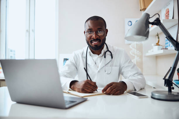 Qualified medical person is writing a prescription Professional medic wearing a stethoscope around his neck while writing notes in his record book qualified report stock pictures, royalty-free photos & images