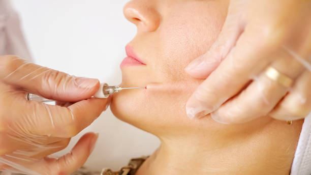 istock Professional cosmetic surgeon injects young woman cheek 1292141574