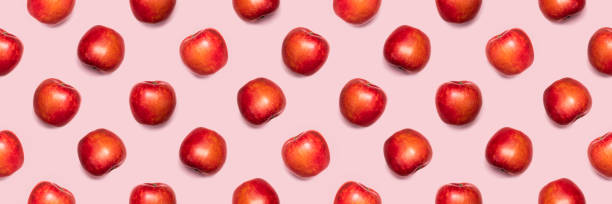 Seamless pattern from apples on a pink background. Seamless background. Seamless background from red apples.