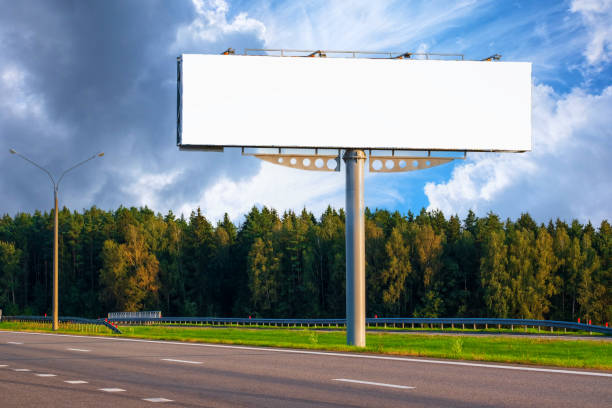 istock Big empty mockup Billboard along a highway with forest on background of blue sky with beautiful clouds. 1292143722