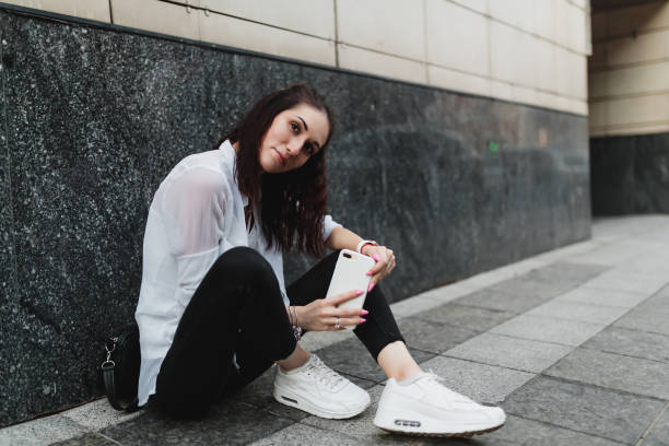 istock Woman uses the phone while sitting on the ground. 1292146179