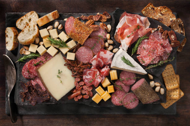 Charcuterie Board Cured Meat and Cheese Platter with Nuts, Crackers and Crusty Bread prosciutto brie stock pictures, royalty-free photos & images