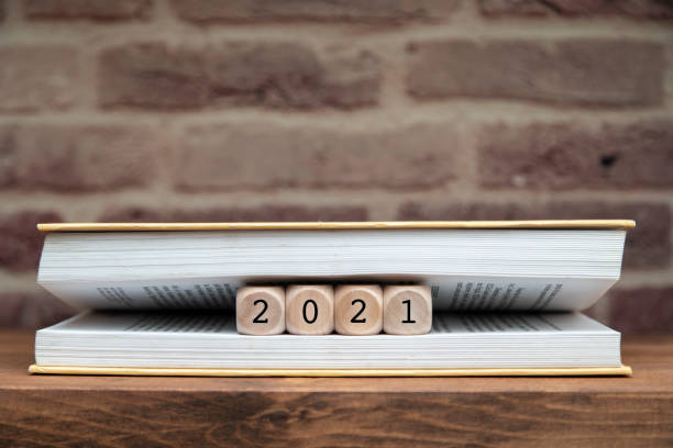 istock New year 2021 written on wooden blocks between book pages on a shelf. 1292147121
