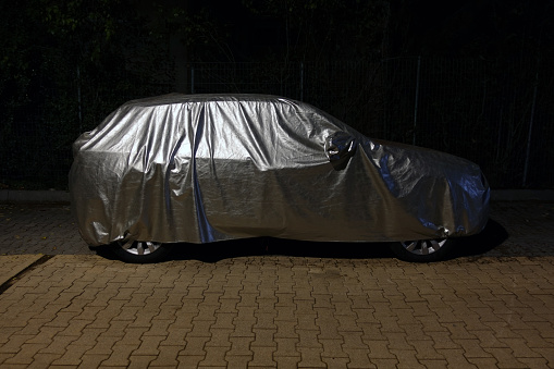 Car with silver protective cover at night.