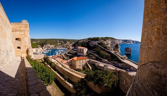 The harbor and the white limestone cliffs of Bonifacio with the famous, picturesque Rock formation „le grain de sable“ viewed from the citadel of Bonifacio, Corsica, France