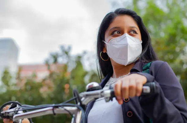Close-up of a Business woman with mask, she is standing and has a bicycle.