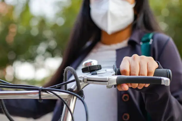 Close-up of a Business woman with mask, she is standing and has a bicycle.