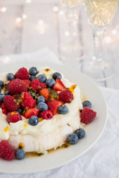 Pavlova with strawberries, blueberries, raspberries and passionfruit Pavlova with strawberries, blueberries, raspberries and passionfruit with Christmas lights and sparkling wine in the background to celebrate the holidays in Australia pavlova stock pictures, royalty-free photos & images