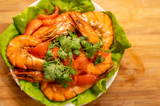 An overhead view of a plate of freshly cooked stir-fried prawn dish during the preparation of Chinese New Year reunion dinner