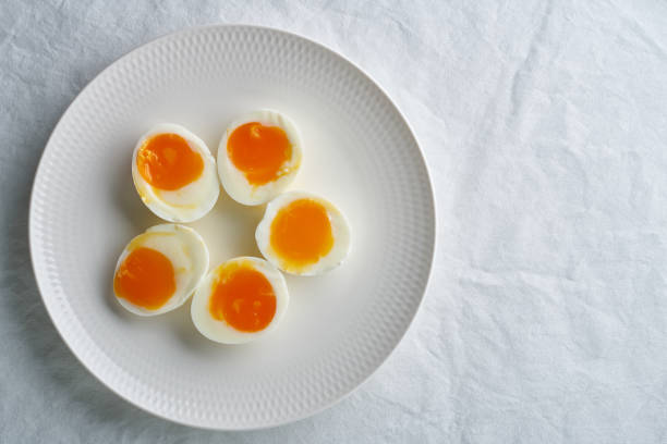 istock Soft-boiled eggs, peeled and cut into two halves, lying on white plate, copy space 1292189818