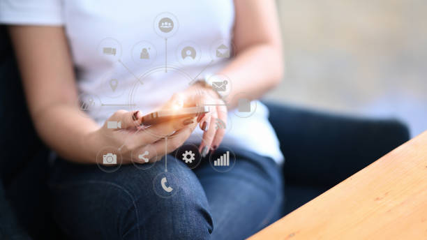 istock Young woman using smart phone and application icon on virtual screen at office in morning light. 1292190799