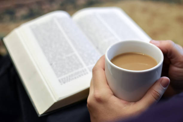 istock Cup of coffee in hands, reading bible 1292194811