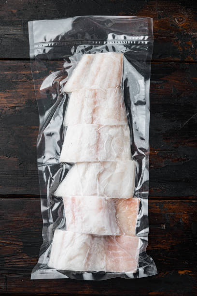 istock Haddock fish skinless in vacuum pack, on dark wooden background, top view 1292205340