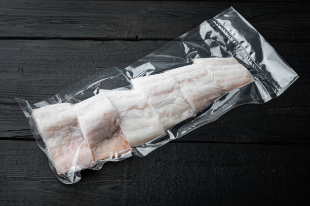 istock Haddock white fish fillet in plastic market pack, on black wooden table with copy space for text 1292206081