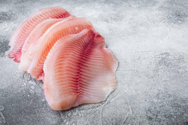 istock Tilapia fish skinless meat, on gray background with copy space for text 1292206091