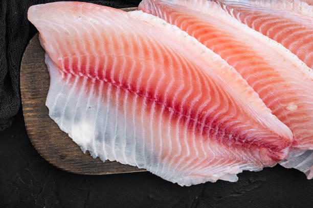 istock Tilapia fish fillet meat, on black background, top view 1292206563