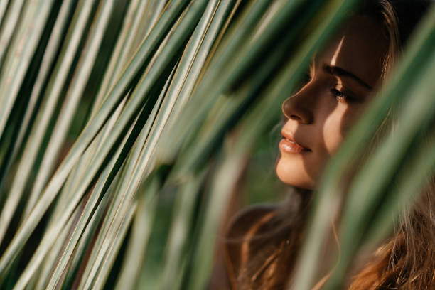 retrato de la mujer tierna mirando fuera de la hoja de palma - leaf epidermis fotografías e imágenes de stock