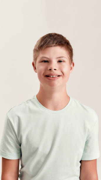 istock Portrait of cheerful disabled boy with Down syndrome smiling at camera while posing isolated over white background 1292208435