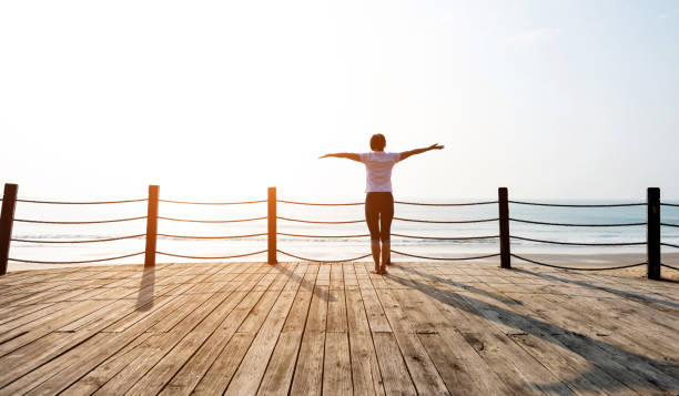 istock Woman standing on boardwalk at the beach 1292209752