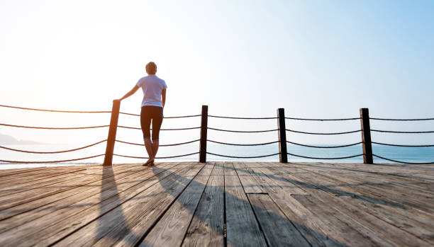 istock Woman standing on boardwalk at the beach 1292209792