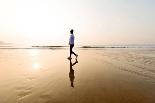 istock Woman walking on the beach at sunset 1292209840