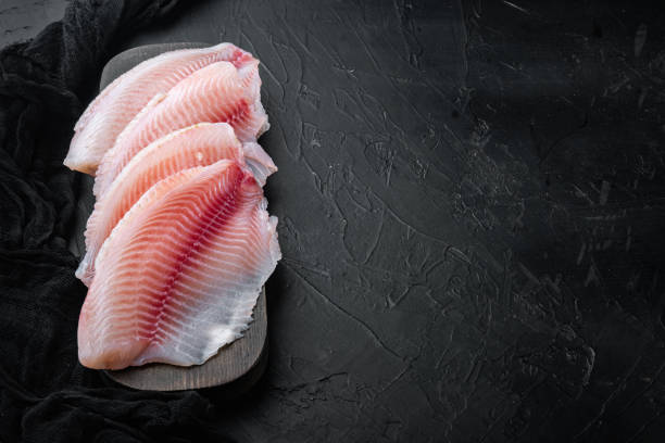 istock Tilapia fish skinless meat, on black background with copy space for text 1292209982