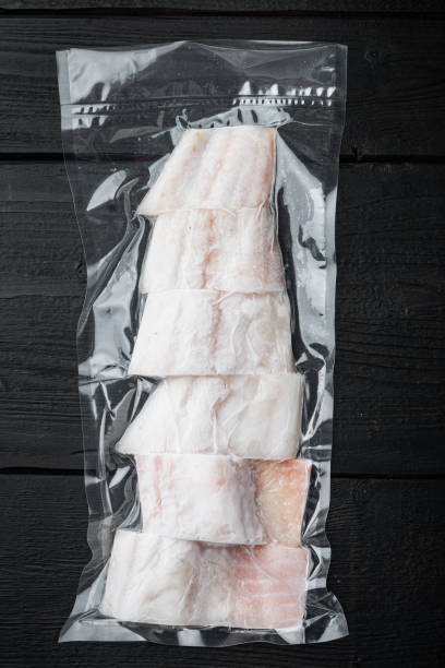 istock Haddock fish skinless in vacuum pack, on black wooden table 1292210475