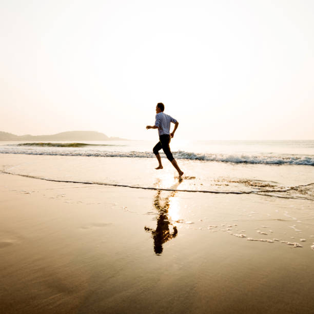 istock Man running on the beach at sunset 1292210916